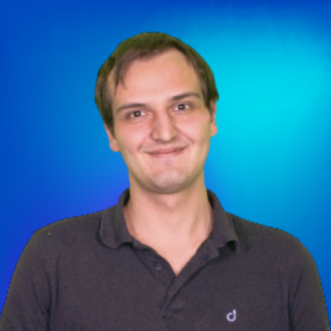 Porträt eines lächelnden jungen Mannes in einem dunklen Poloshirt vor blauem Hintergrund.