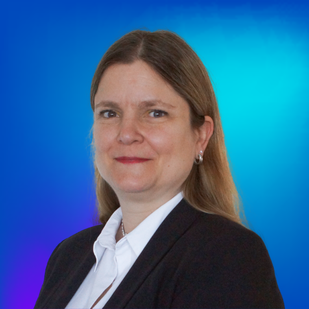 Frau mit langen braunen Haaren und Anzug lächelt vor blauem Hintergrund.