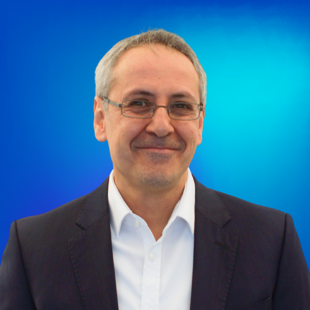 Lächelnder Mann in Anzugjacke mit Brille vor blauem Hintergrund.