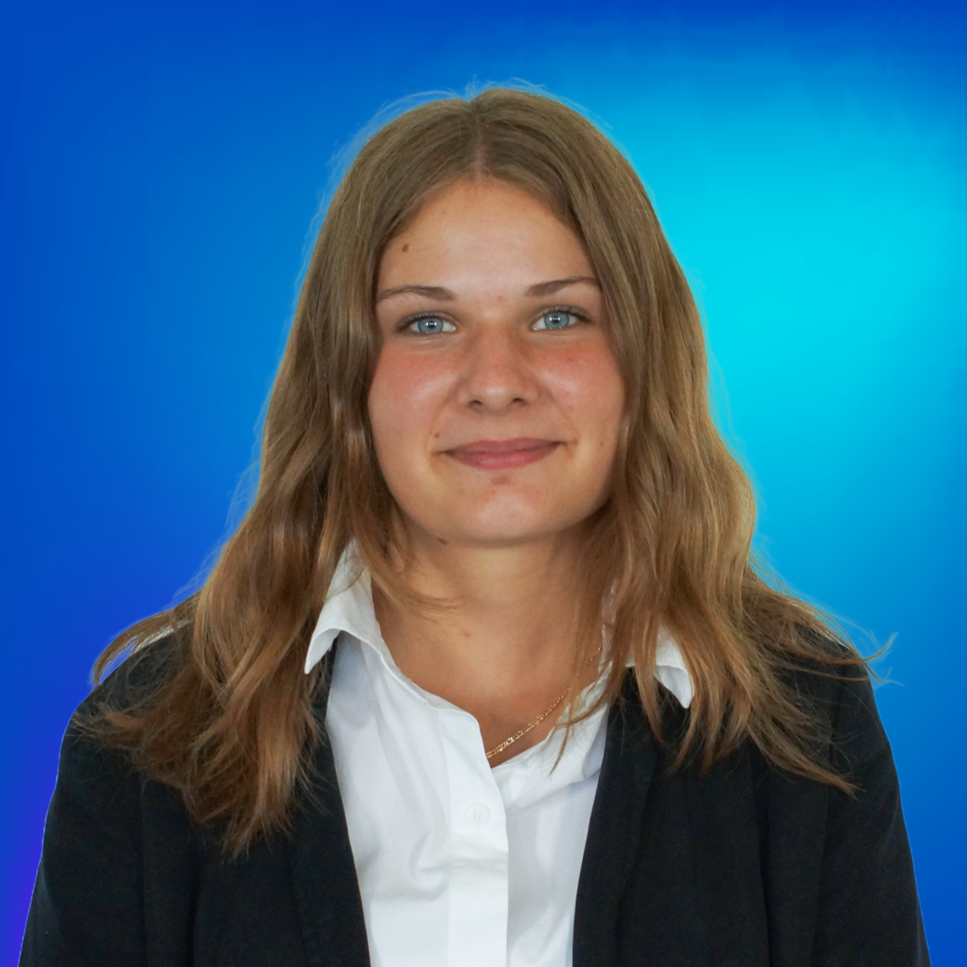 Porträt einer lächelnden jungen Frau mit blonden Haaren, blauen Augen, weißem Hemd und dunklem Blazer.