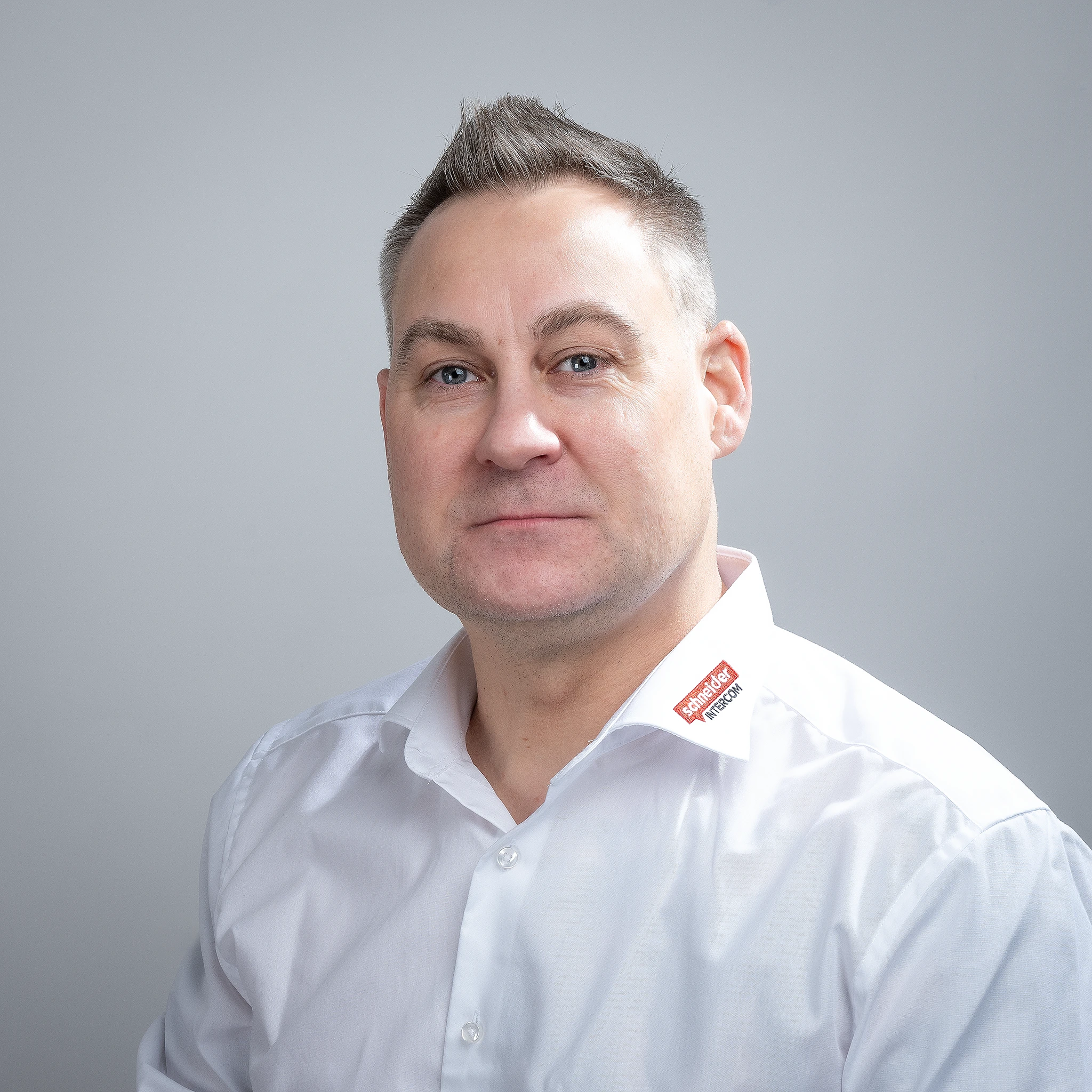 Mann in weißem Hemd mit Schneider Intercom Logo.
