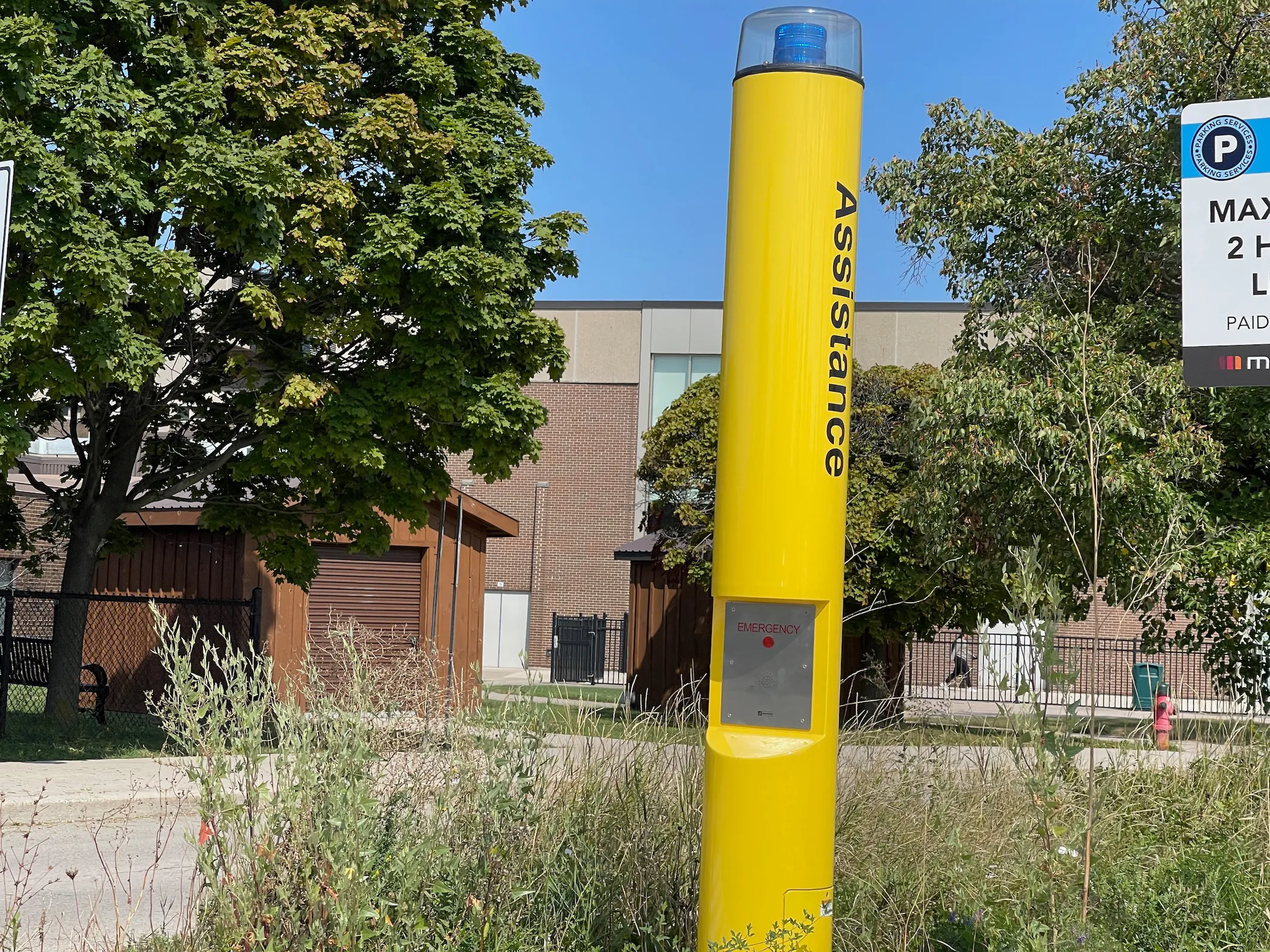 Yellow emergency assistance communication tower with beacon in an outdoor public area