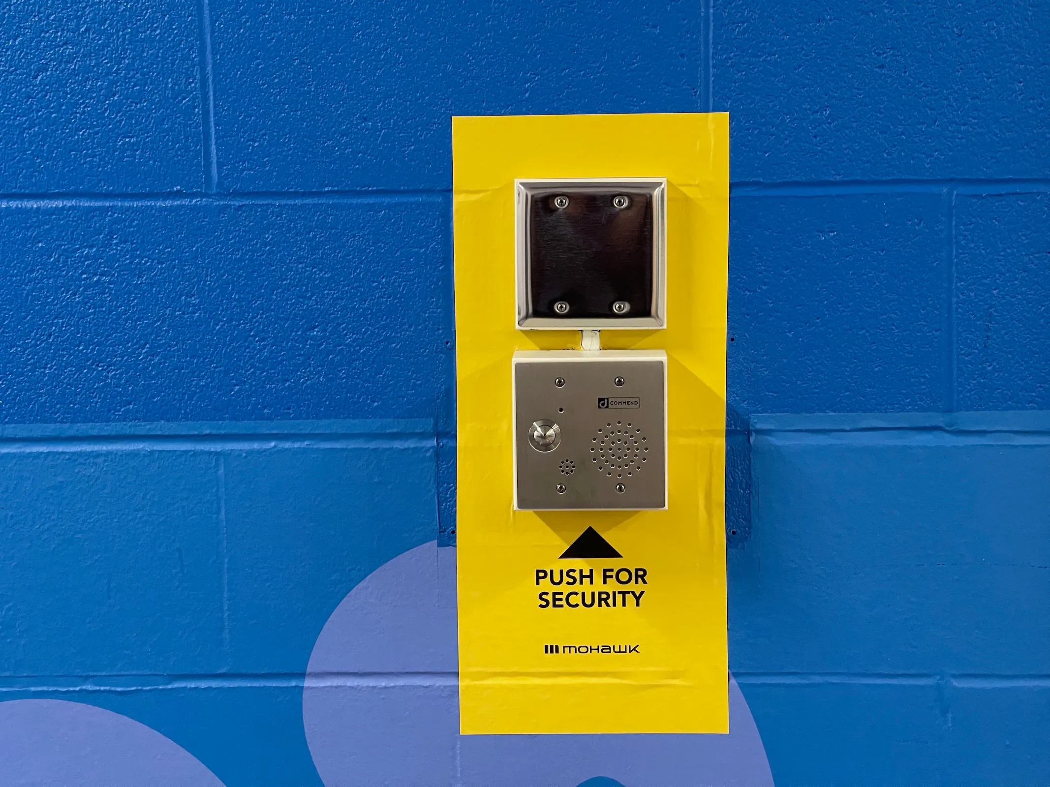 Wall-mounted emergency intercom with security call button for campus communication.