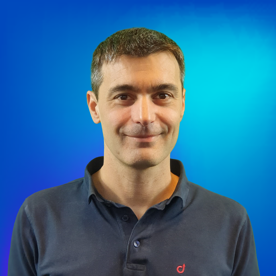 Lächelnder Mann in blauem Poloshirt vor blauem Hintergrund.