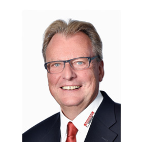 Porträt eines lächelnden Mannes mit Brille, Anzug und roter Krawatte.