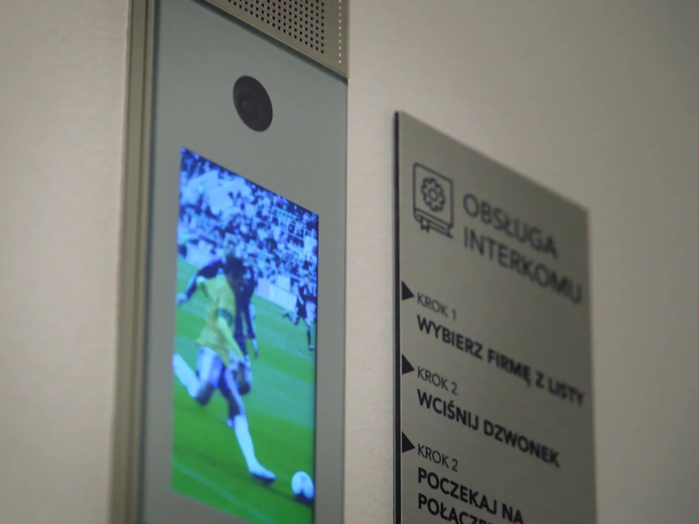 Wall-mounted video intercom screen displaying an image of a football match Video intercom display showing football match image