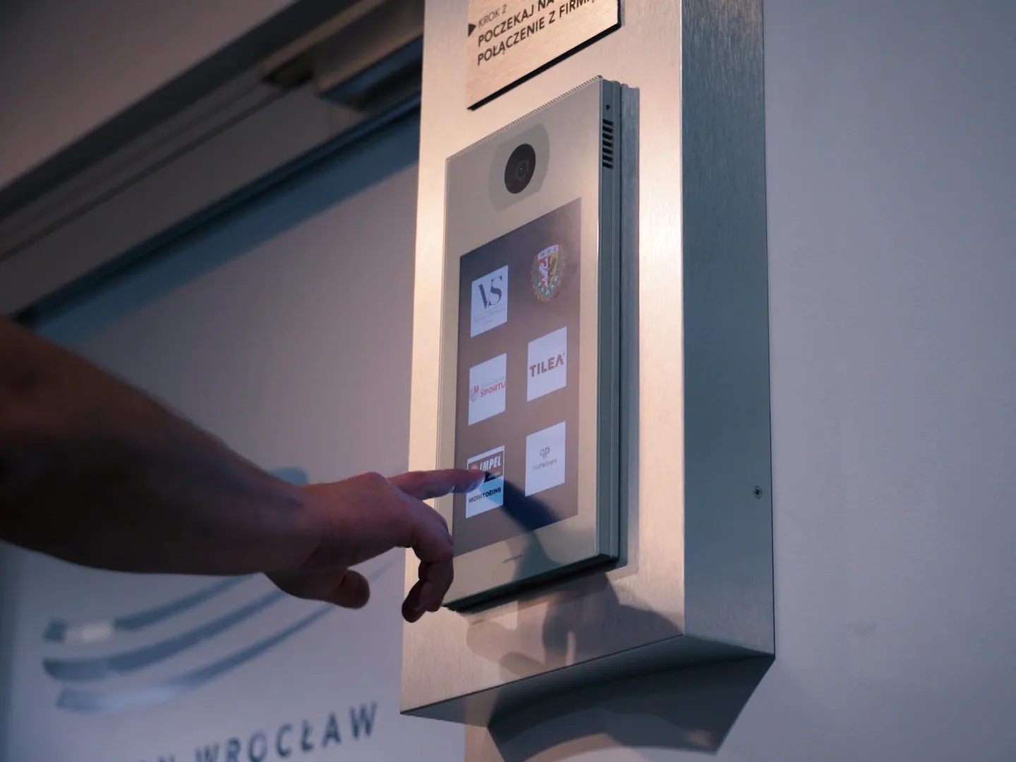 User interacting with touchscreen intercom system for visitor access and communication control Touchscreen intercom panel for secure building access communication