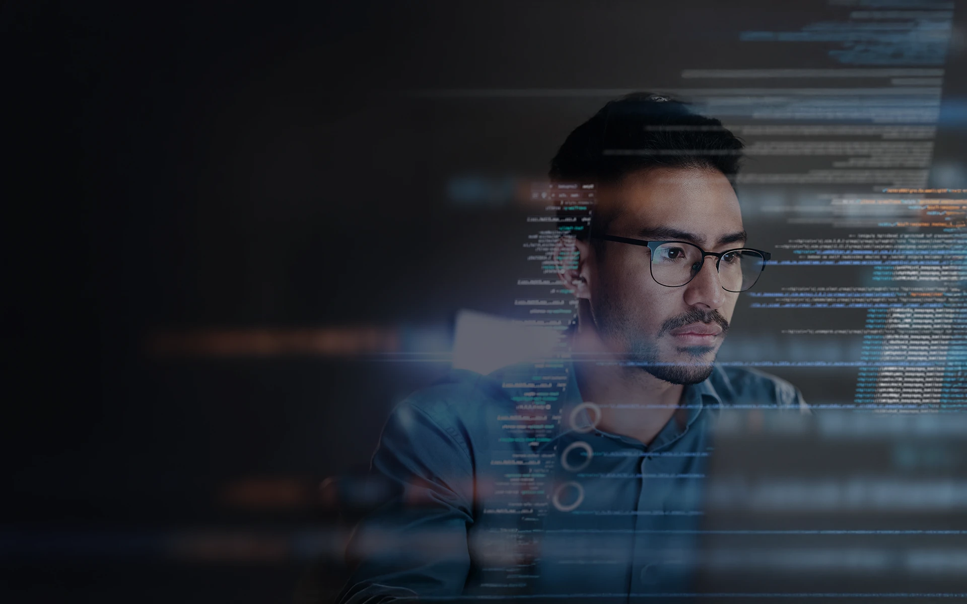 Softwareentwickler bei der Arbeit Ein konzentrierter Mann mit Brille blickt auf einen Bildschirm mit Code, der eine Kommunikations- oder Sicherheitslösung entwickelt.