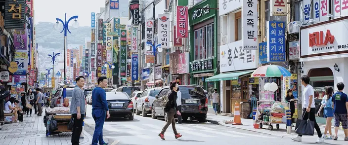 Bustling Korean City Street Busy street in a Korean city with many vertical signs, pedestrians, and parked vehicles.