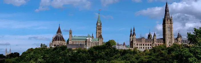 Parlament Kanadas, Ottawa Kanadisches Parlament mit Peace Tower, Uhr, Flagge, blauem Himmel, grünen Bäumen.