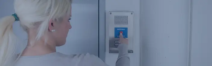 Notruf an der Sprechanlage Frau drückt roten Notfallknopf an einer Sprechanlage.