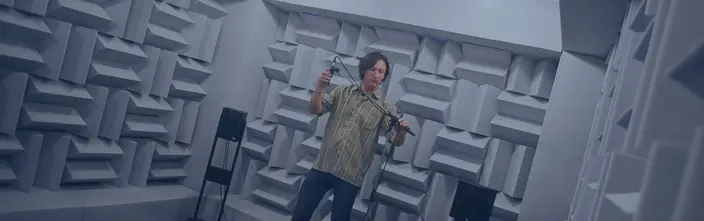 Audio-Test in Akustiklabor Mann stellt Mikrofon in schallgedämmtem Raum ein.