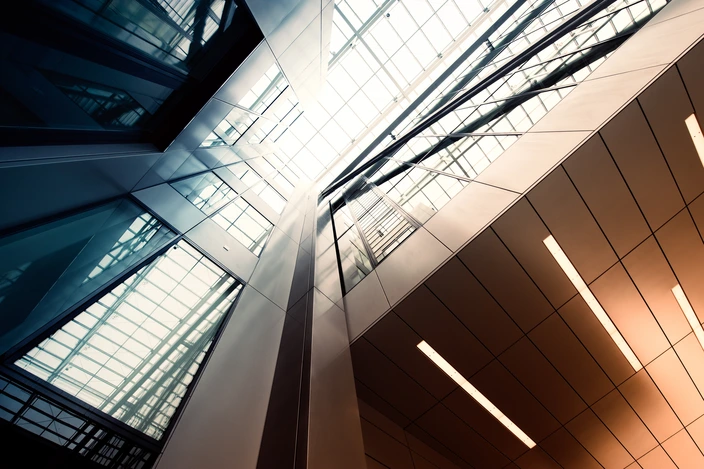 Moderne Architektur im Gebäude Innenansicht eines modernen Gebäudes mit Glasdach, Metallstrukturen und warmen Lichtleisten.