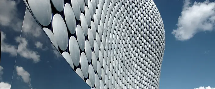Selfridges Birmingham Modern Facade Close-up of Selfridges building's metallic disc facade reflecting sky and clouds, modern architecture.
