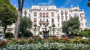 Grand Hotel Facade and Garden Elegant 'Le Grand Hotel' building with gardens, fountain, and trees on a sunny day.