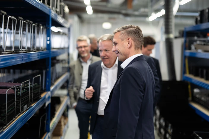 Unsere Sprechanlagen in der Fertigung Männer inspizieren Sprechstellen auf blauen Regalen in einer Produktionsanlage.