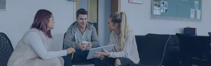 Junge Leute im Gespräch Drei junge Menschen im Gespräch, eine mit Tablet, eine mit Tasse, in hellem Raum.