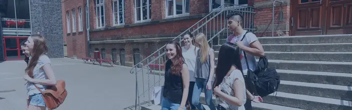 Schüler verlassen fröhlich die Schule Jugendliche Schüler verlassen lachend ein Schulgebäude mit Backsteinfassade.