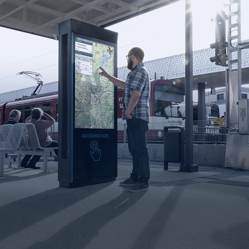 Reisender nutzt digitale Notruf- und Informationssäule am Bahnhof für Sicherheit und Service