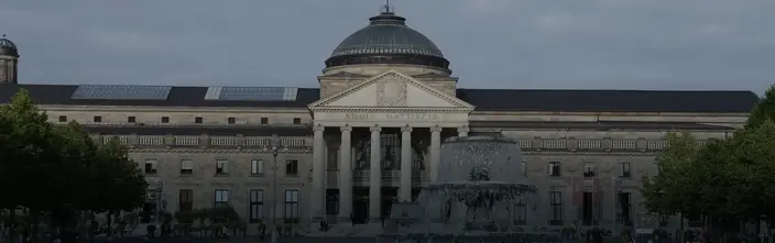 Grand Kurhaus Building with Fountain A grand classical building with a dome, columns, "AQUIS MATTIACIS" text, and a large fountain in front.