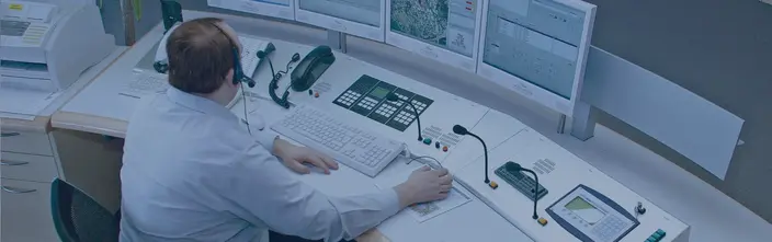 Operator an Kommunikationspult Operator nutzt eine Kommunikationslösung an einem Mehrbildschirm-Kontrollpult.