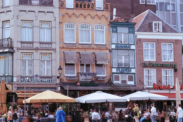 Lebhafte europäische Straßenszene Historische europäische Gebäude, Straßencafés mit Menschen unter Sonnenschirmen.