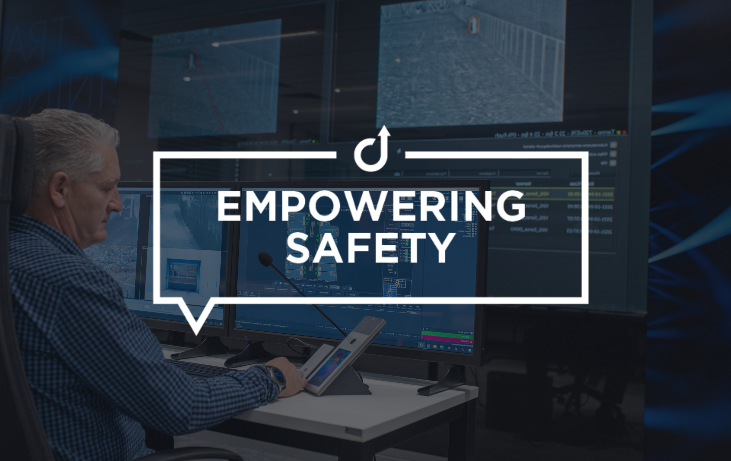 Security officer at control console with monitors, operating an intercom.