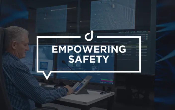 Security officer at control console with monitors, operating an intercom.