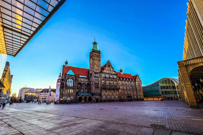Neues Rathaus Dresden im Sonnenlicht Dresdner Neues Rathaus mit Uhrturm, rotem Dach, modernen Gebäuden, Personen auf dem Platz.