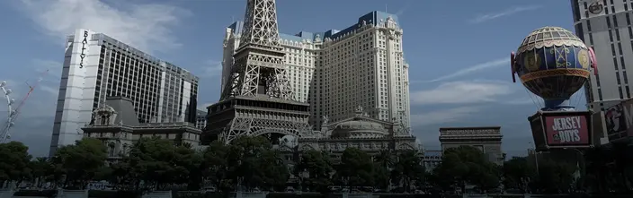 Paris Las Vegas & Bally's am Strip Paris Las Vegas Hotel mit Eiffelturm-Nachbau, Bally's und Heißluftballon unter blauem Himmel.